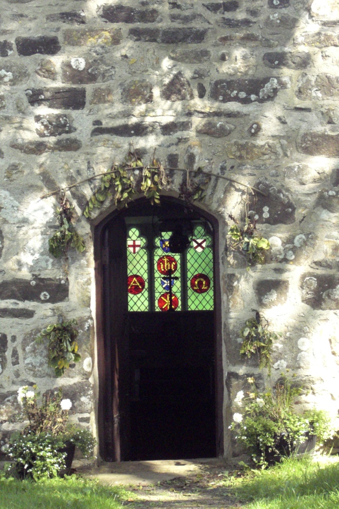 St Tudwens church, stained glass window through door